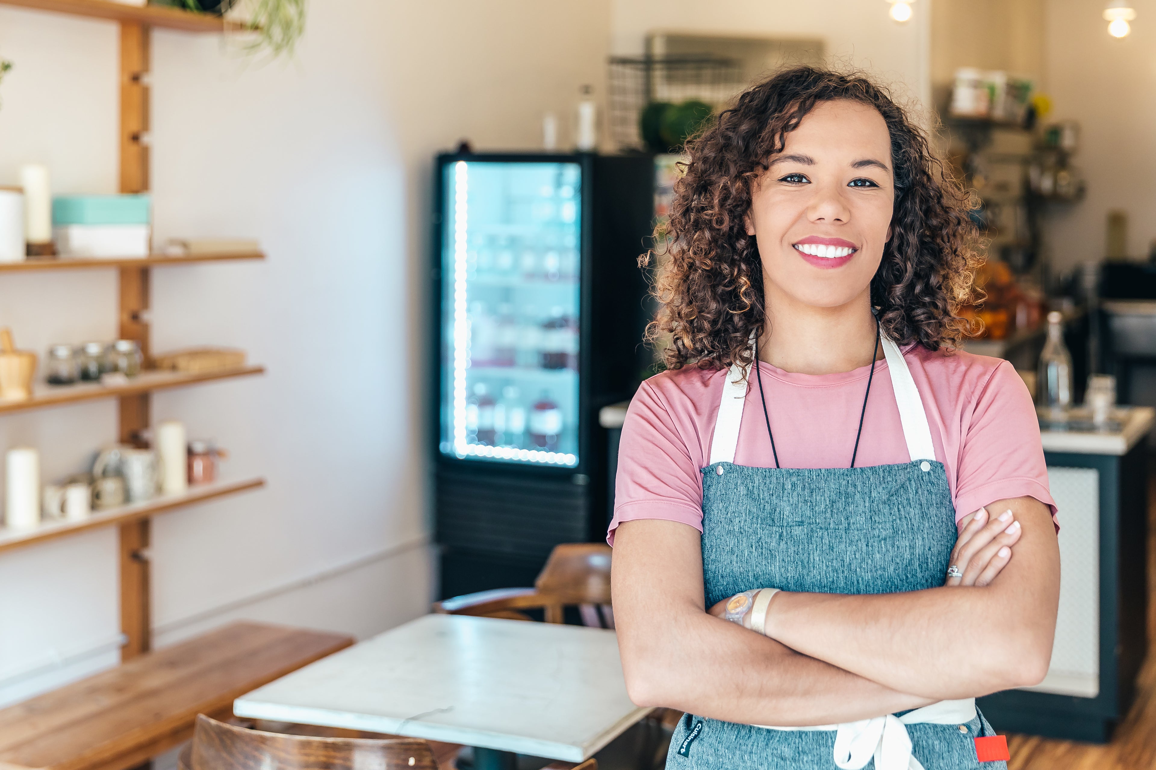 a-barista-smiles-proudly-stood-in-her-cafe