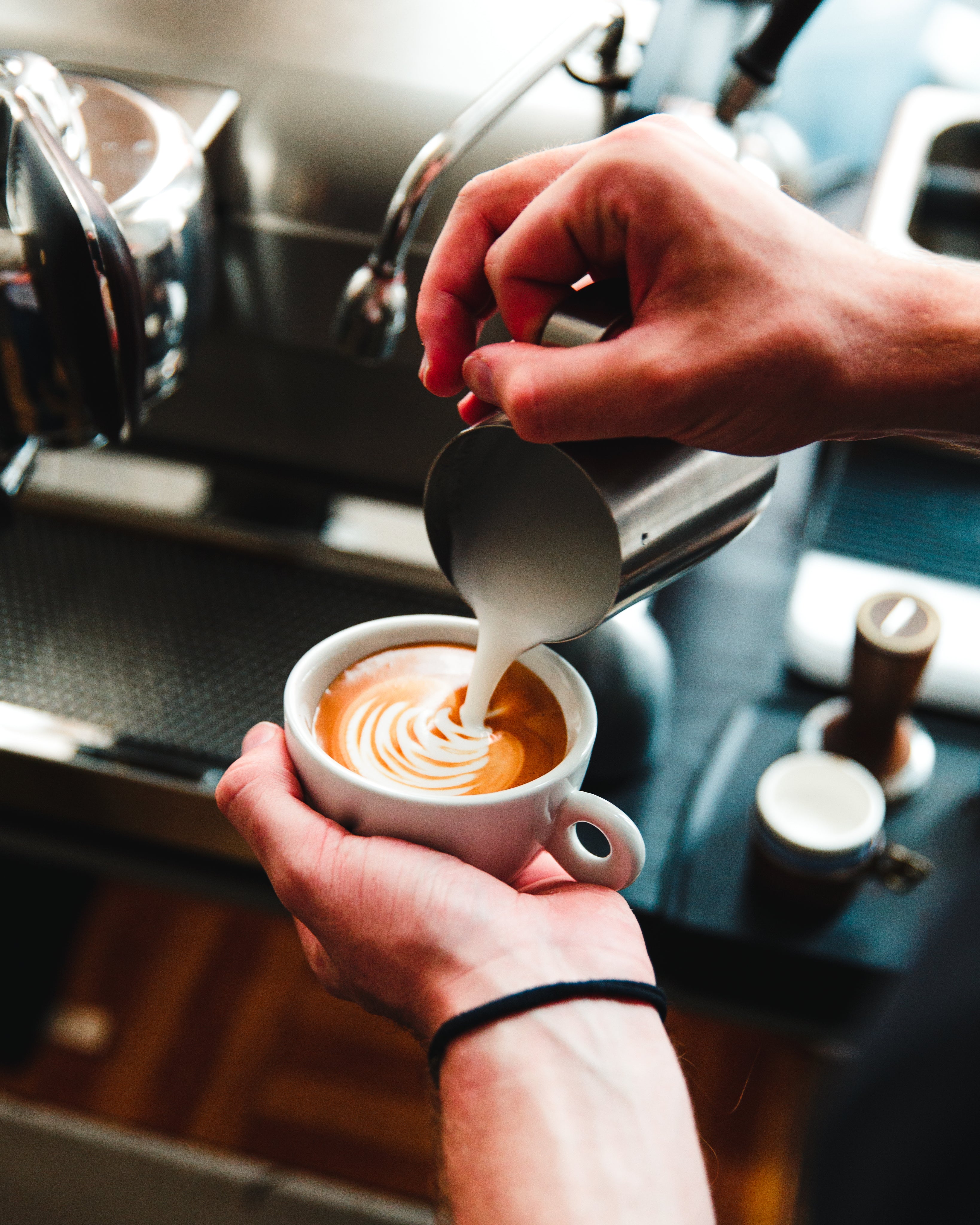 barista-pours-steamed-milk-on-espresso